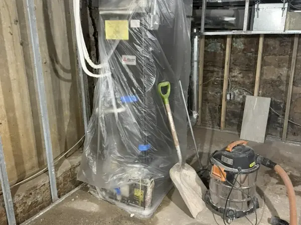Plastic containment around a furnace with a shop vac in a Corona, NY cellar being dried