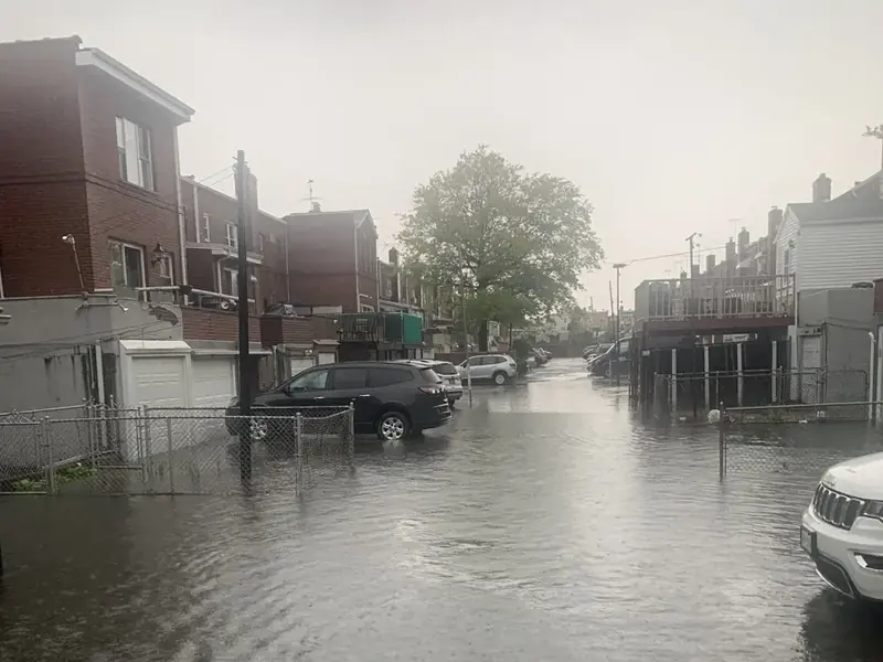 Flooded street between attached brick houses in northern Queens during a heavy rainstorm