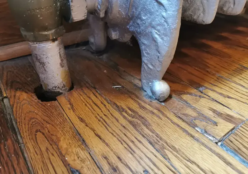 Leaking steam radiator valve staining an oak floor in a Corona, Queens home